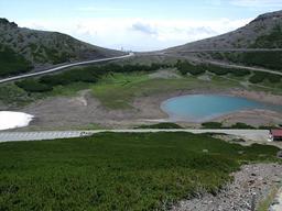 県境の道路最高地点と渇水時には消える鶴が池(拡大します)